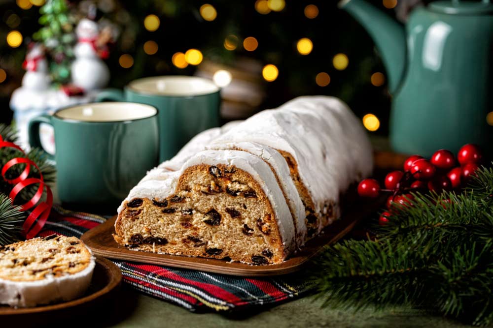 粉砂糖をまぶしたドイツのクリスマス菓子シュトーレンとホットドリンクの温かいテーブルセッティング