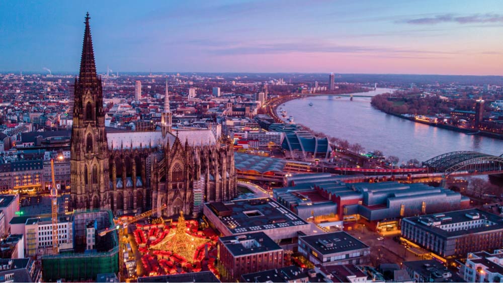 夕暮れのケルン大聖堂とその前に広がるクリスマスマーケットの夜景