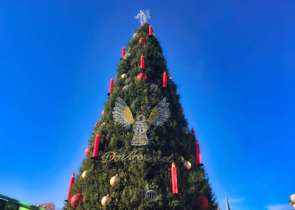 ドルトムントのクリスマスマーケットにそびえる巨大なクリスマスツリーと青空