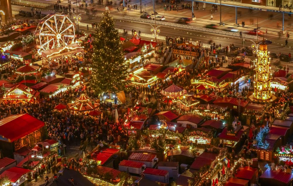 夜のドレスデンのクリスマスマーケットとライトアップされた大きなツリー