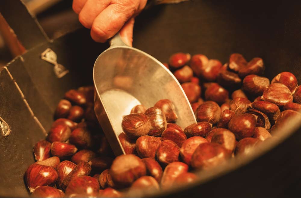 ドイツのクリスマスマーケットで販売される焼き栗をすくう手元のクローズアップ