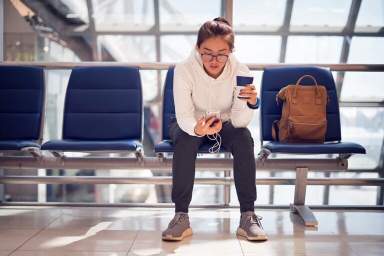韓国の空港ロビーのベンチで、SIMカードの設定や到着後の連絡のためスマートフォン操作をする旅行者