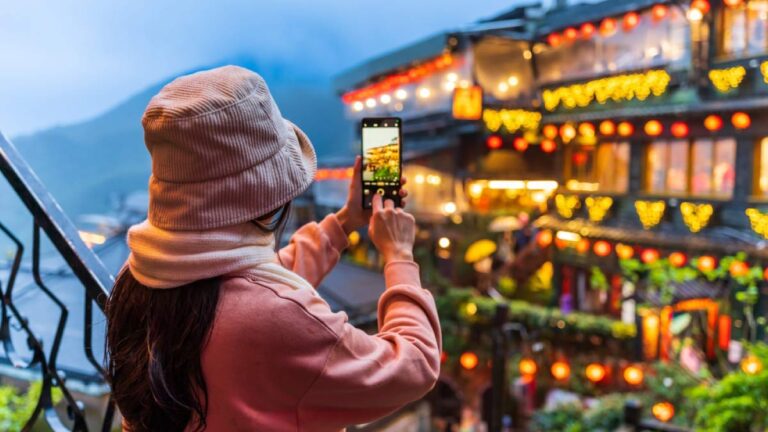台湾・九份の夜景をスマートフォンで撮影する女性旅行者