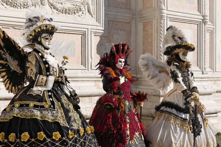 イタリア・ヴェネツィアのカーニバルで、絢爛豪華な衣装と仮面を身にまとった人々が佇む様子