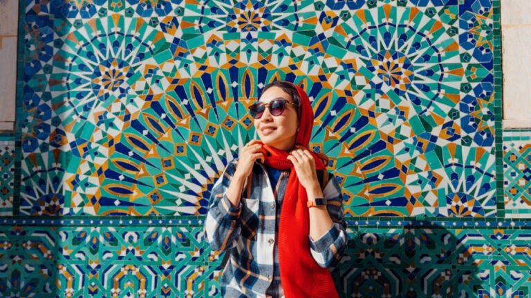色鮮やかなタイルの前で春の日差しを楽しむ女性旅行者。3月がベストシーズンの海外旅行先を象徴するフォトジェニックなシーン。