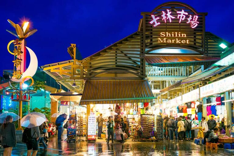 夜に賑わう台湾・台北の定番観光スポット「士林夜市（士林市場）」の看板と街歩きを楽しむ人々の様子