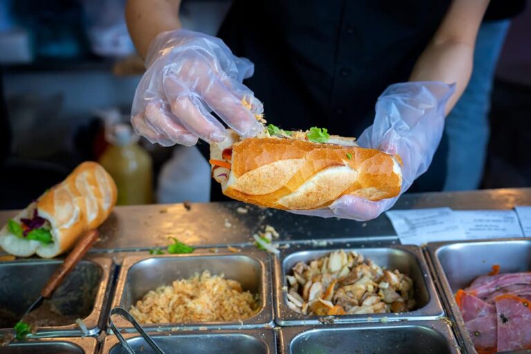 ベトナム・ホーチミンの屋台で、フランスパンに肉や野菜などの具材を挟んでバインミーを作る様子