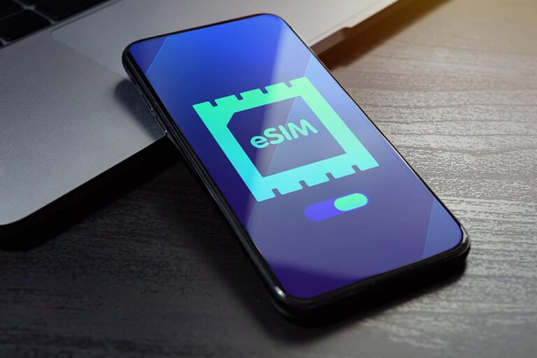 ノートパソコンの横に置かれたスマートフォンの画面に、eSIMのチップアイコンが表示されている様子