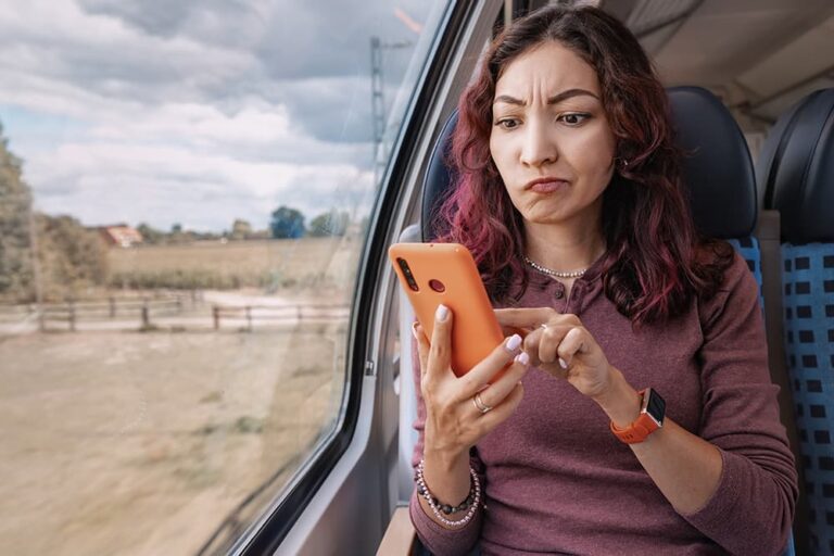 移動中の電車内でスマートフォンの通信がうまくつながらず、困った表情で画面を操作する女性