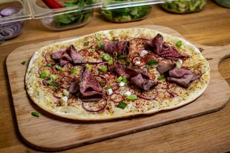 コルマールで人気のアルザス地方の郷土料理「タルト・フランベ(フラムクーヘン)」の盛り付け例。薄焼きの生地に玉ねぎや牛肉がトッピングされている