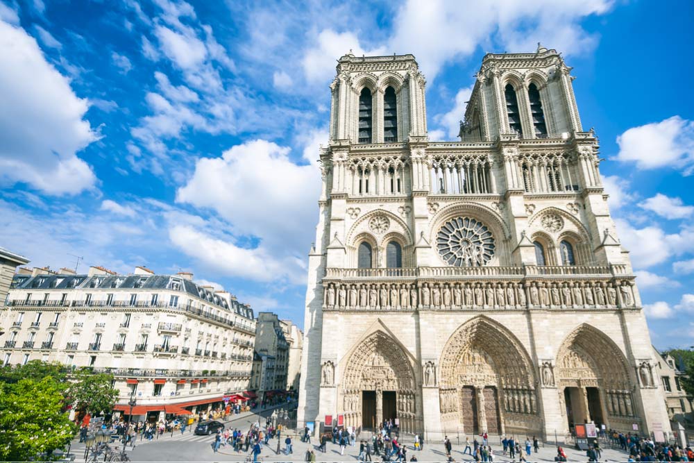 パリ観光の象徴・ノートルダム大聖堂の壮麗な外観と、晴天のもと広場を行き交う観光客の様子
Show less
