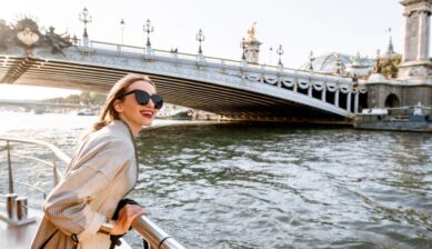 セーヌ川クルーズでパリの街並みを楽しむ女性旅行者の笑顔とアレクサンドル3世橋の風景