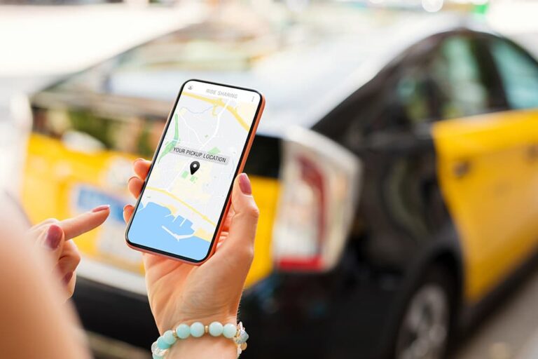 タクシーを背景に、配車アプリの地図画面で乗車位置を確認するスマートフォンを手に持つ様子、Airaloのデータ通信で移動中も快適にアプリを利用できるメリットを示す一枚