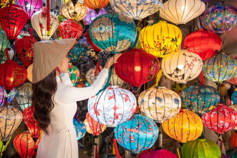 ホイアンのランタン市場で、ノンラーをかぶった女性が色とりどりのランタンを手に取って選んでいる様子