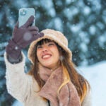 雪景色の中でスマートフォンを掲げて自撮りする女性