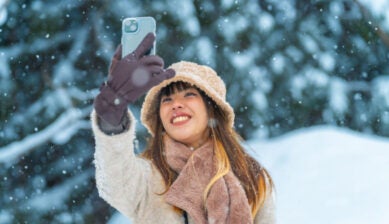 雪景色の中でスマートフォンを掲げて自撮りする女性