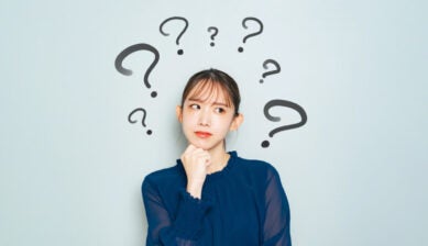 複数のクエスチョンマークに囲まれ、顎に手を当てて考え込む女性の表情