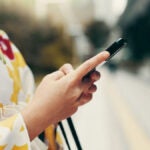 着物姿の女性が屋外でスマートフォンを操作している手元の様子