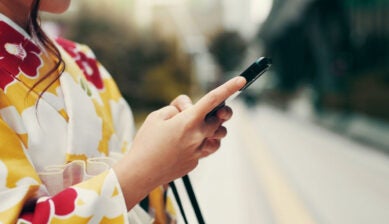 着物姿の女性が屋外でスマートフォンを操作している手元の様子