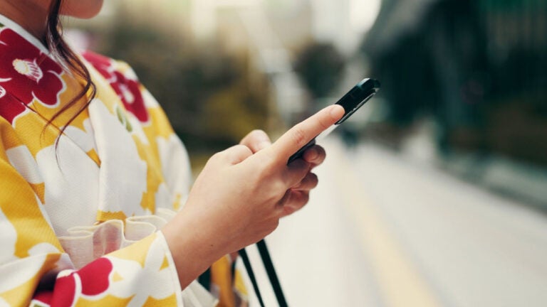 着物姿の女性が屋外でスマートフォンを操作している手元の様子