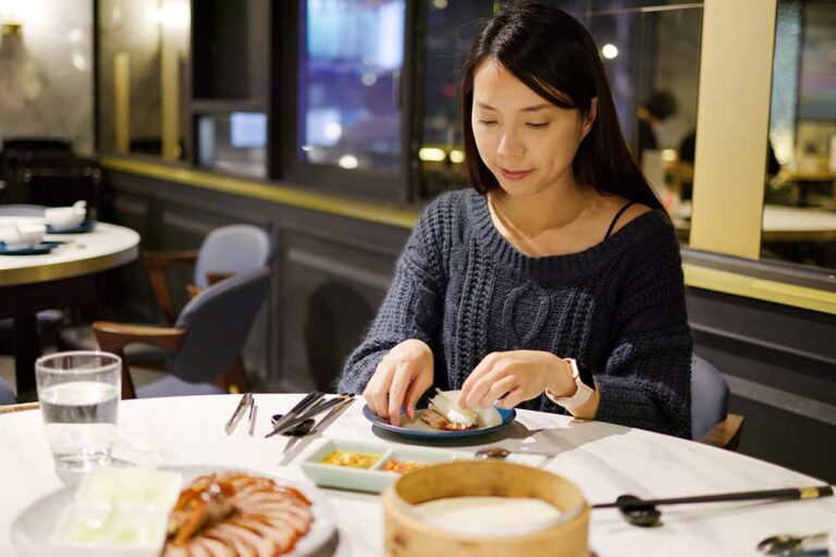 薄餅に北京ダックを巻いて味わう女性。北京観光で食べたい名物グルメの一皿