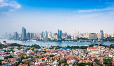 鼓浪嶼の歴史的街並み越しに望む廈門市街の高層ビル群。都市と島の魅力が融合する代表的な観光風景