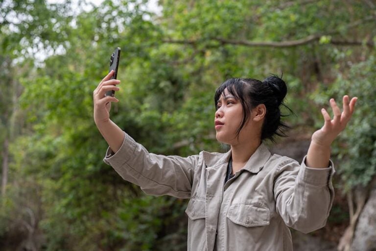 自然の中でスマートフォンを掲げて電波を探し、つながらず困惑する女性
