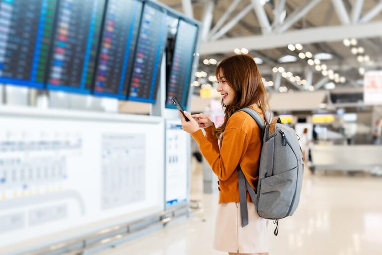 空港でスマートフォンを操作し、トリファが復旧しない場合の代替通信手段を確認する旅行者