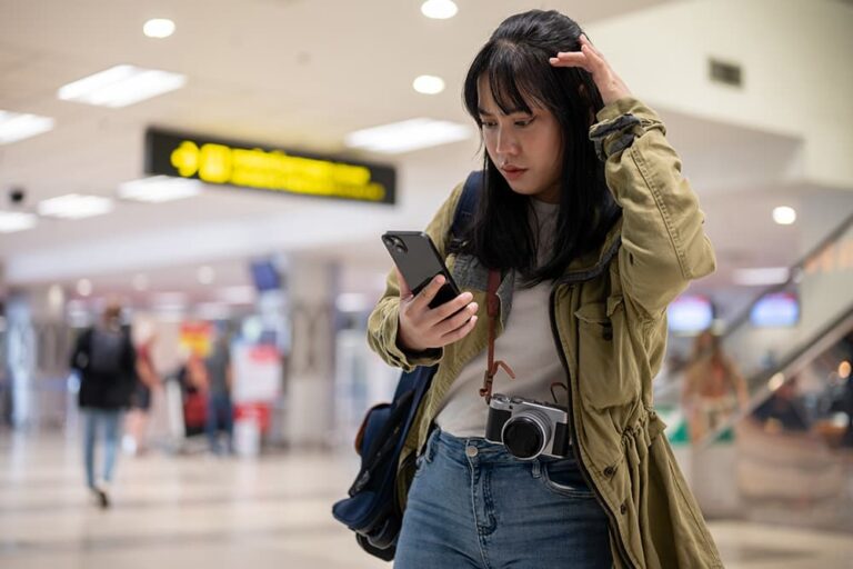 空港でスマートフォンを確認し、トリファeSIMの開通・設定状況に戸惑う旅行者