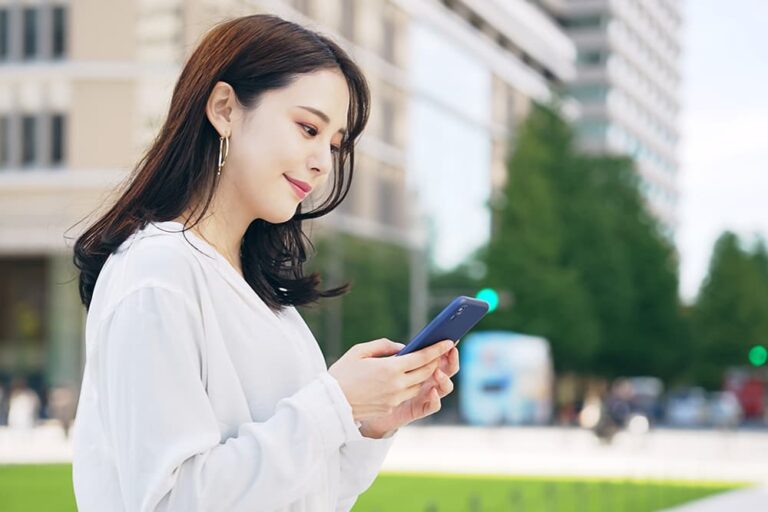 海外の街中でスマートフォンを操作し、楽天モバイルの海外ローミング設定を確認する旅行者