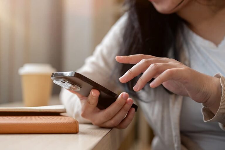 カフェでスマートフォンを操作し、トリファ公式サポートへの問い合わせを進める旅行者