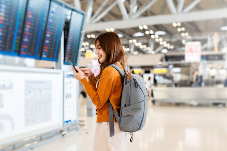 空港でスマホを確認する旅行者が、海外で使うデータローミングの設定方法を確認している様子