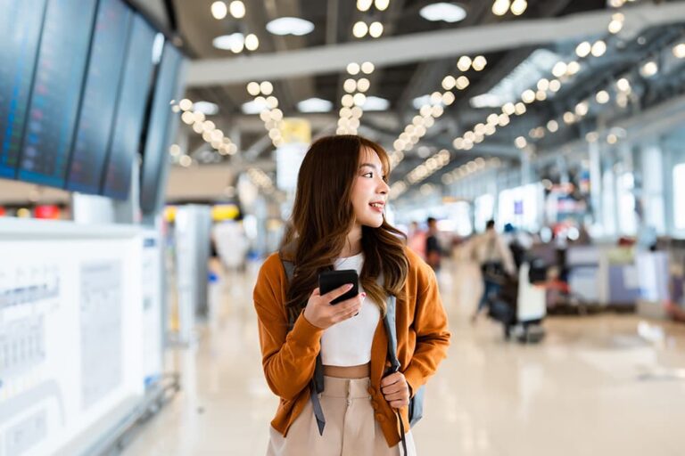 空港でスマホを持つ旅行者が、ahamo海外利用前にデータローミング設定を確認する様子