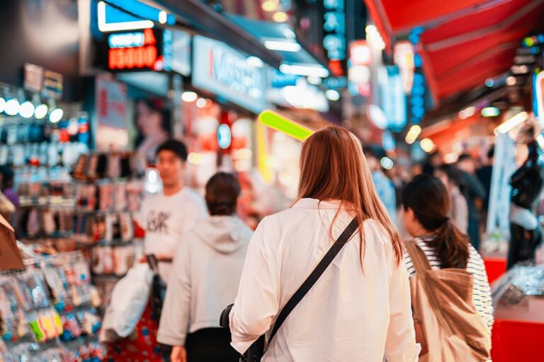 夜の賑やかな韓国ソウル、明洞のショッピングストリートで買い物する女性観光客、韓国お土産探しの定番エリア