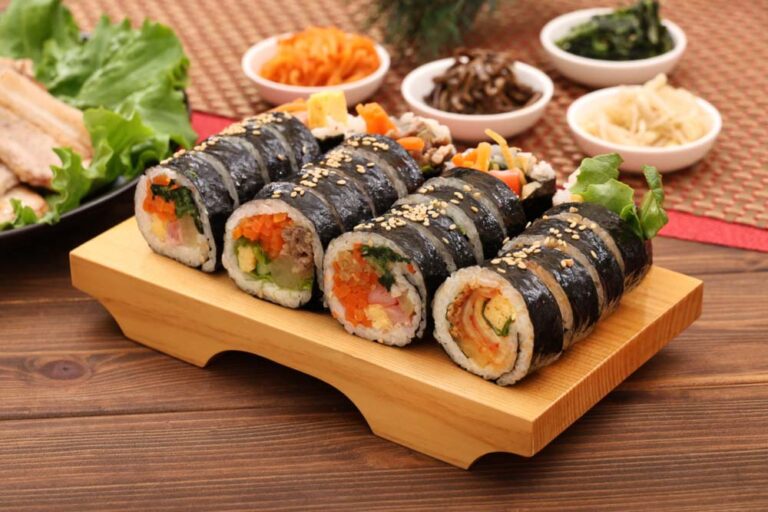 にんじんや卵、野菜が入った韓国料理キンパを木製プレートに並べた写真