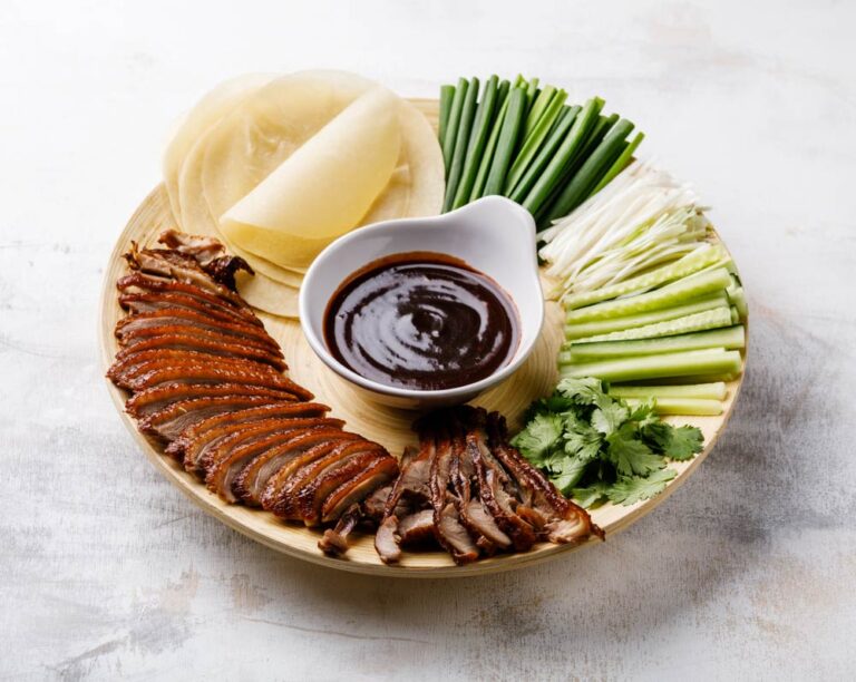 北京の名物グルメ・北京ダックをカットした鴨肉と皮、香味野菜、甜麺醤ソース、薄餅とともに盛り付けた一皿の写真