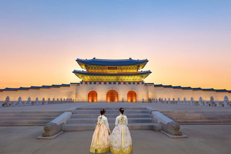 夕暮れ時の景福宮の前に韓服姿で立つ2人の女性