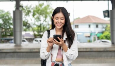 駅のホームでスマートフォンを操作している旅行者の女性