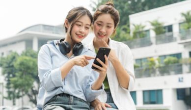 旅行中の2人の女性が、スマートフォンで通信サービスを利用しながら情報を確認している様子