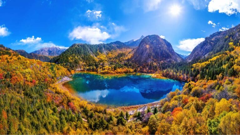 中国・九寨溝のエメラルド色の湖と紅葉に彩られた山々の風景