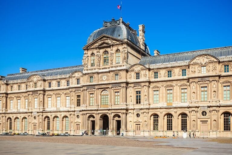 澄み渡る青空のもと、歴史的で荘厳な建築美が際立つパリのルーヴル美術館（ルーヴル宮殿）の外観   