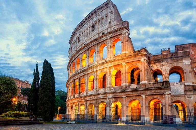 夕暮れ時に温かい光でライトアップされた、ローマの歴史的建造物コロッセオの重厚な佇まい
