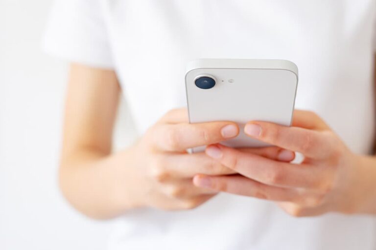 スマートフォンを手に設定画面を確認する様子。自分のスマホがeSIM対応機種か調べる方法を示すイメージ