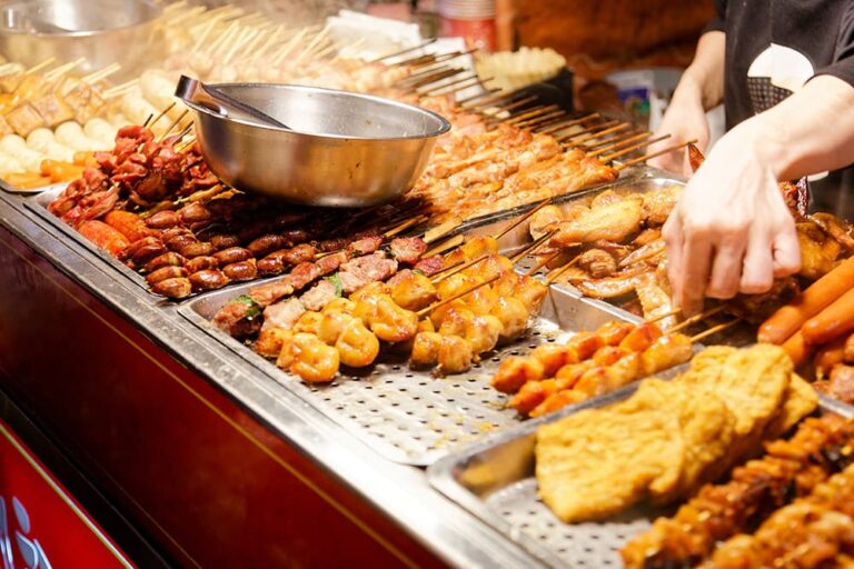 台湾の夜市で多種多様な串焼き料理がずらりと並び、屋台の店主が調理をしている活気ある様子
