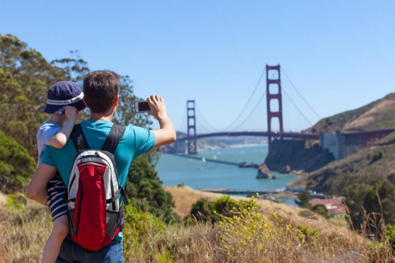 子どもを肩車してゴールデンゲートブリッジを撮影する旅行者。子連れでのアメリカ旅行のイメージ。
