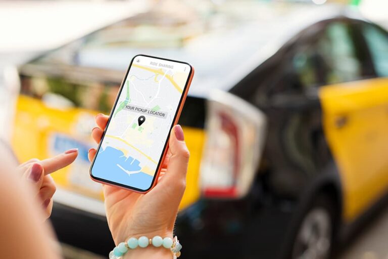 ライドシェアアプリで現在地を確認するスマートフォンと背景のタクシー。
