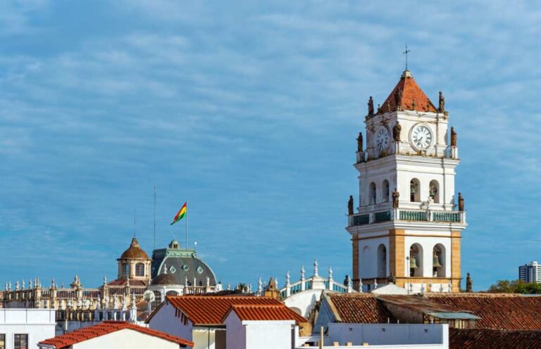 ボリビアの憲法上の首都スクレの白い街並みとカテドラルの時計塔、ボリビア国旗がはためく風景