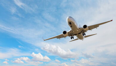 青空と白い雲を背景に着陸態勢に入る旅客機を真下から見上げた迫力ある一枚