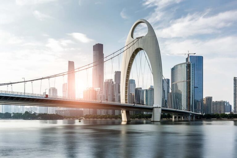  珠江に架かる猟徳大橋の独特なアーチと広州の高層ビル群に差し込む朝日