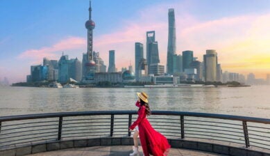 夕暮れの外灘から浦東のスカイラインを眺める赤いワンピースの女性旅行者